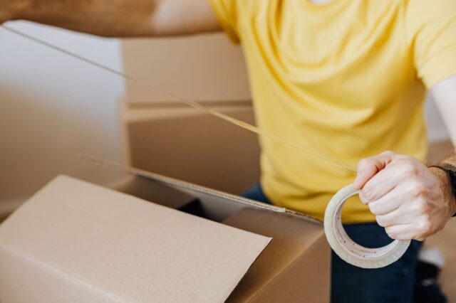 ダンボールを梱包する男性