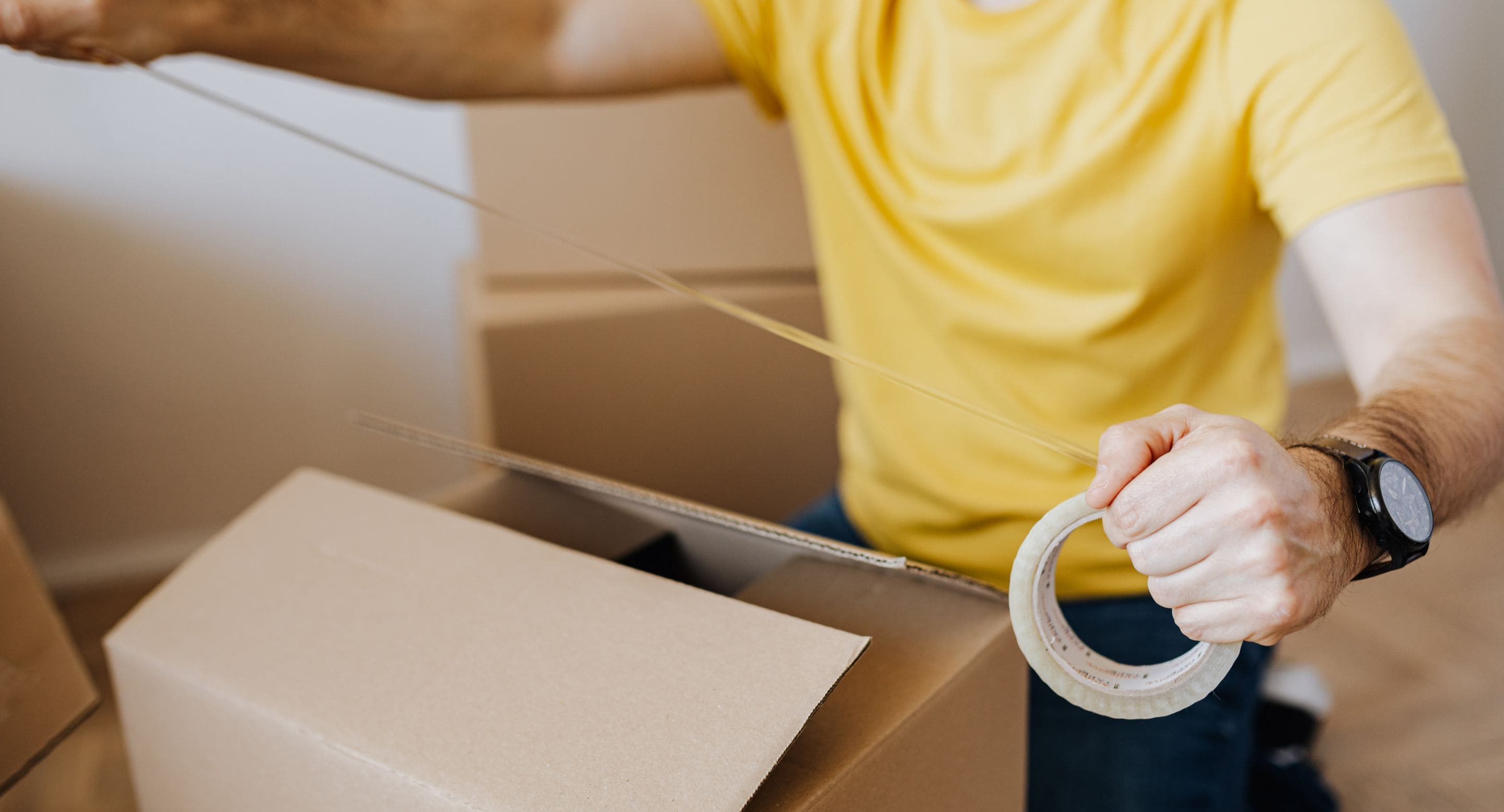 ダンボールを梱包する男性